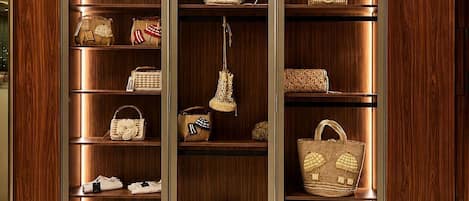 Un mueble de madera con varios estantes, cada uno exhibiendo distintos bolsos y accesorios.