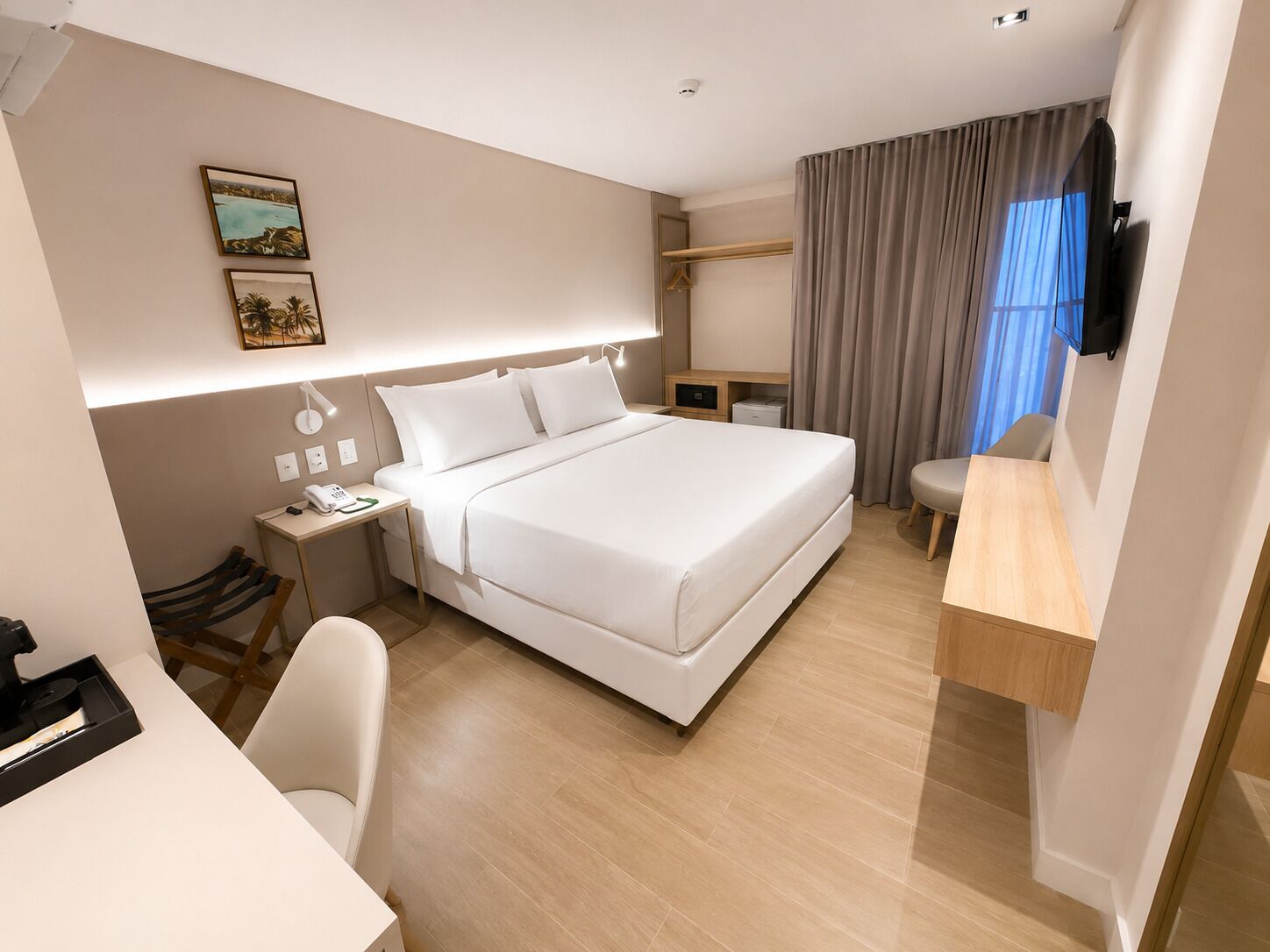 Une chambre d’hôtel moderne, dotée d’un grand lit, d’une table de chevet, d’une lampe et d’un bureau avec une chaise.