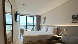 A hotel room with a bed, a sofa, a desk, a chair, and a view of the ocean. - Holanda Gold Hotel Praia de Tambaú (João Pessoa)