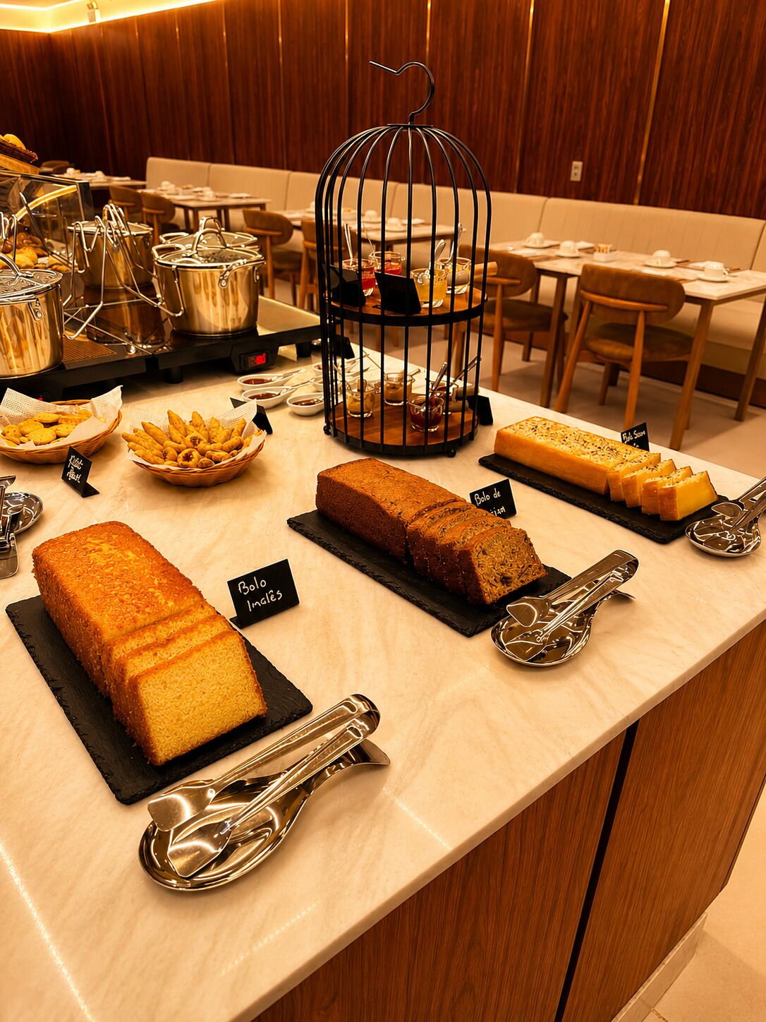 Un comptoir de buffet proposant diverses pâtisseries et agrémenté d’une cage à oiseaux décorative.