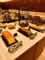 Un comptoir de buffet proposant diverses pâtisseries et agrémenté d’une cage à oiseaux décorative.