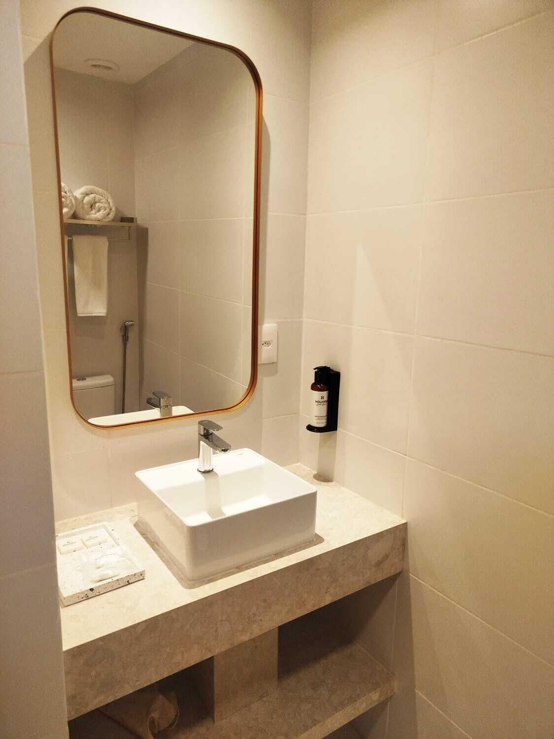 A bathroom with a white sink, a mirror with a wooden frame, and a towel rack with towels.