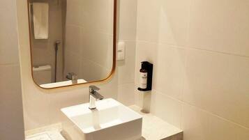 A bathroom with a white sink, a mirror with a wooden frame, and a towel rack with towels.
