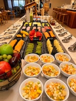 Un bufé con frutas, verduras y platos preparados.