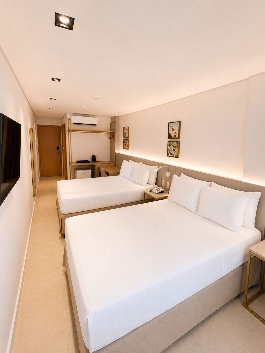 A hotel room with two beds, a desk, a chair, and a television.