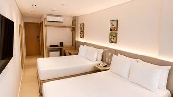 Habitación de hotel con dos camas, un escritorio, una silla y un televisor.
