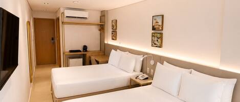 A hotel room with two beds, a desk, a chair, and a television.