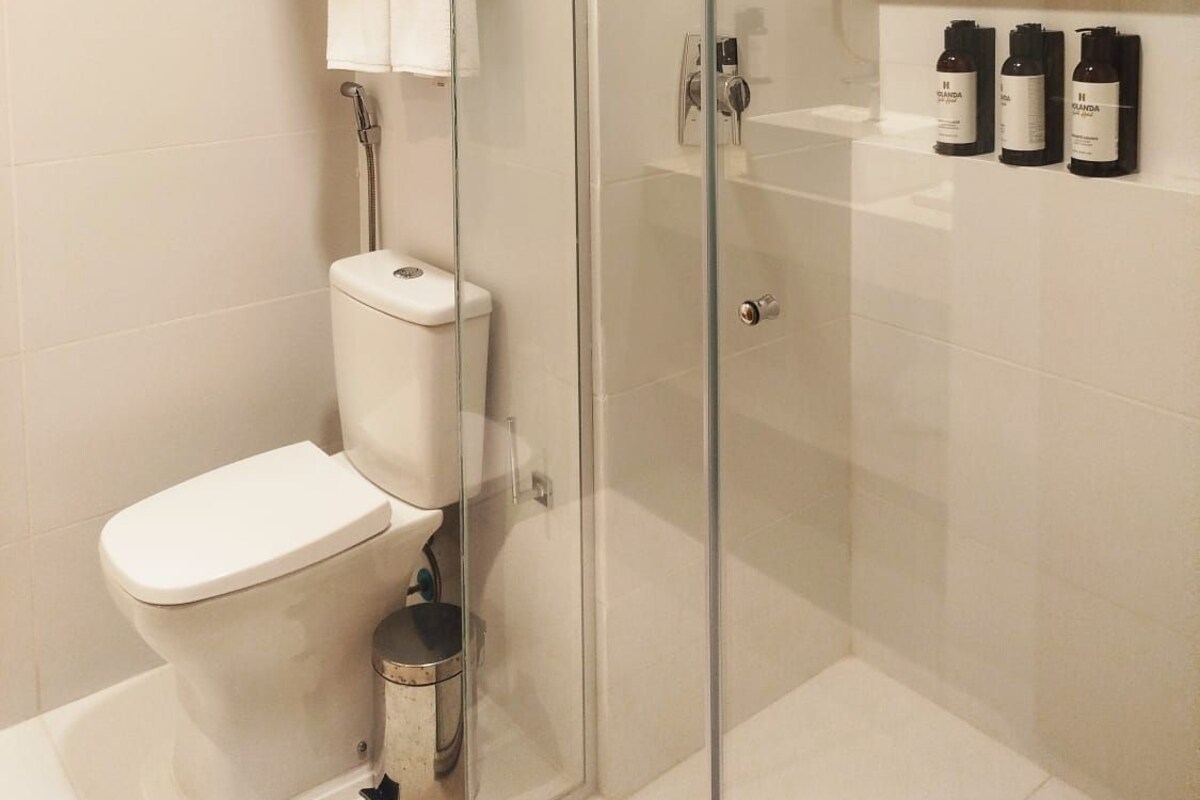 Ein modernes Badezimmer mit einer Duschkabine, einer Toilette und einem Ablagebereich für Pflegeprodukte.