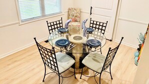 Un coin repas avec une table ronde en verre, des chaises en métal noir et une porte blanche en arrière-plan.