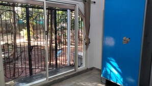 A room with a sliding glass door leading to an outdoor area with a metal gate and trees. - Charming 4-bedroom villa with AC and WiFi in enchanting Bommayapalayam Peaceful, (Bommayapalayam)