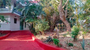 A courtyard with a red pathway leading to a white building with a balcony. - Charming 4-bedroom villa with AC and WiFi in enchanting Bommayapalayam Peaceful, (Bommayapalayam)