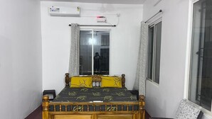 A bedroom with a bed, a chair, a window, and an air conditioning unit. - Charming 4-bedroom villa with AC and WiFi in enchanting Bommayapalayam Peaceful, (Bommayapalayam)
