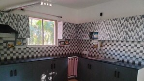 A kitchen with checkered tile backsplash, dark cabinets, a pink towel, and a window with a view of greenery. - Charming 4-bedroom villa with AC and WiFi in enchanting Bommayapalayam Peaceful, (Bommayapalayam)