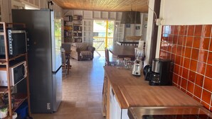 Eine Küche mit Kühlschrank, Mikrowelle und Kaffeemaschine. Es gibt einen Essbereich mit Tisch und Stühlen.