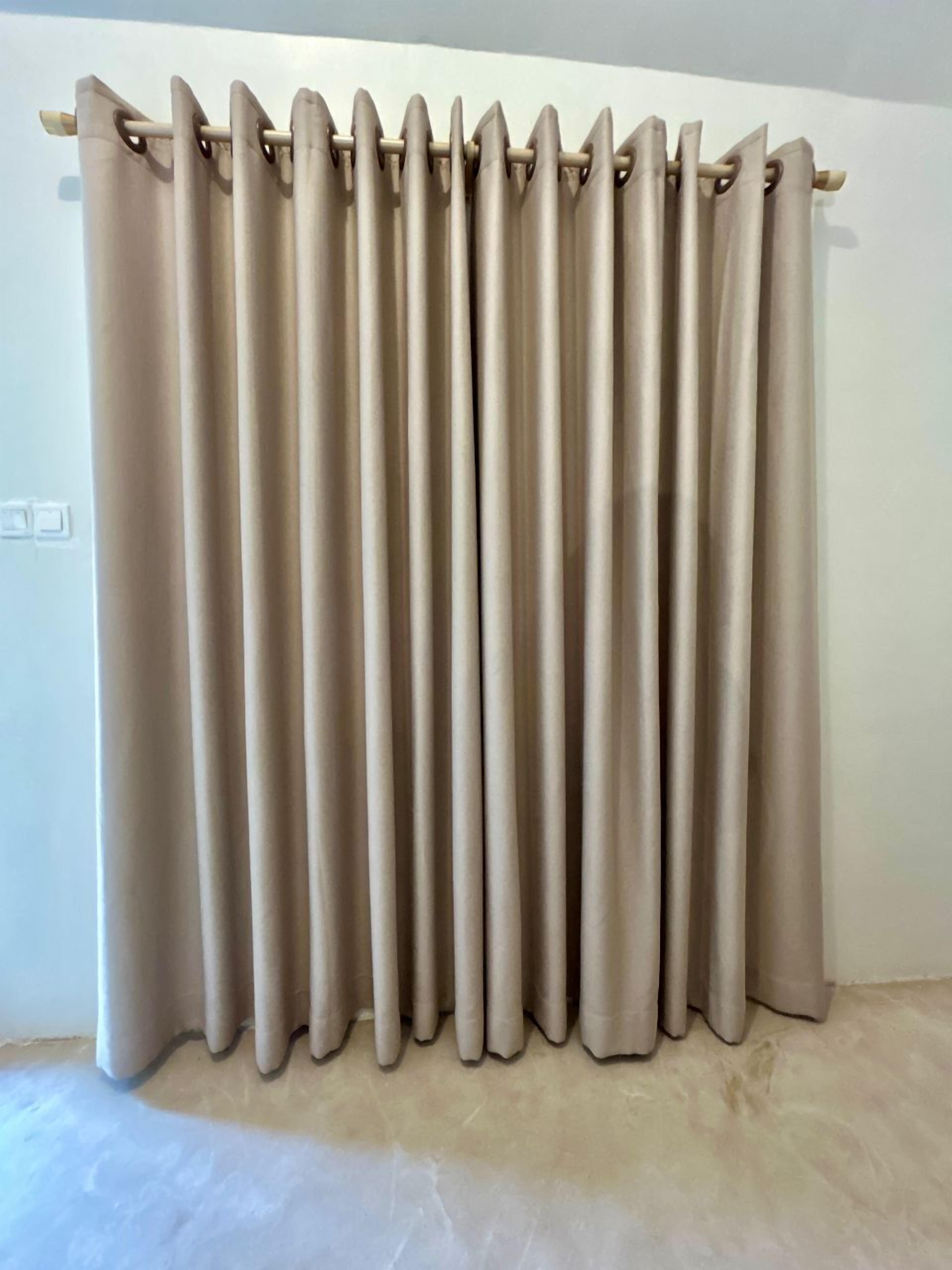 A beige curtain with a rod, a light switch, and a marble floor.