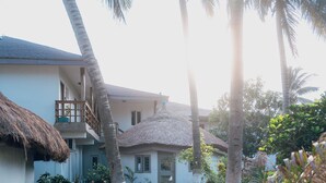 Un resort tropical con una casa de techo de paja, palmeras y un jardín cuidado.