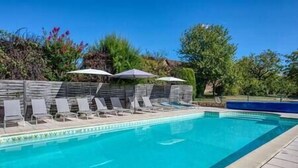 Ein Schwimmbecken mit Liegestühlen und Sonnenschirmen.