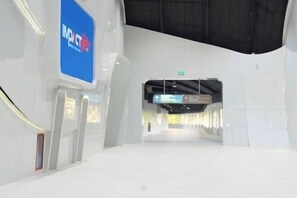 A modern interior with a white floor, a blue sign, and a ceiling with a black structure. - Impact Stay Muangthong C3-C9 (Pak Kret)