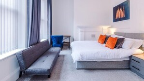 Quarto de hotel moderno com cama, um banco, escrivaninha e lareira.