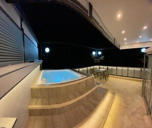 Area piscina interna moderna con idromassaggio, posti a sedere e una scala che conduce a un piano superiore.