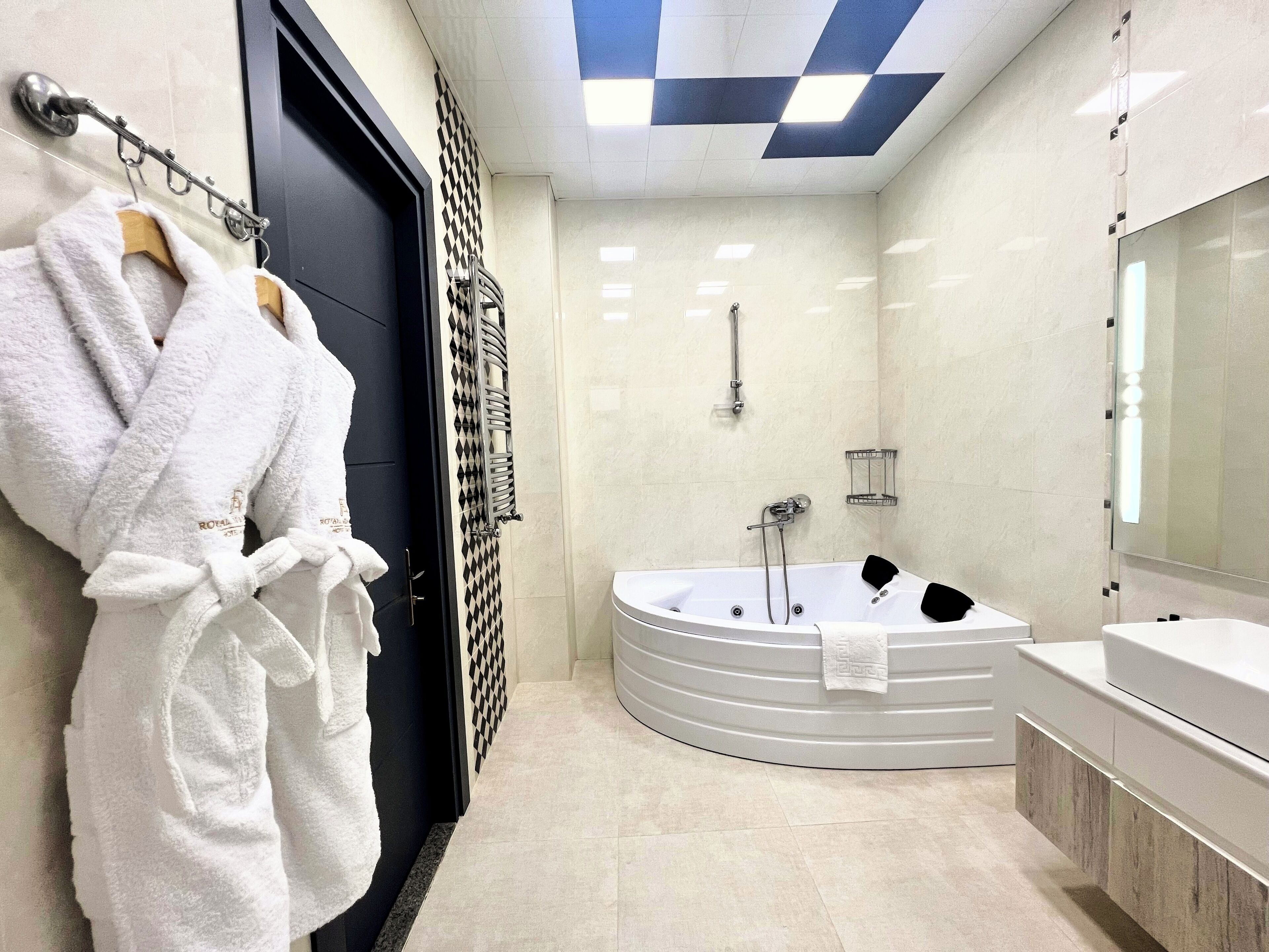 A modern bathroom with a bathtub, a large mirror, and a towel rack with robes.