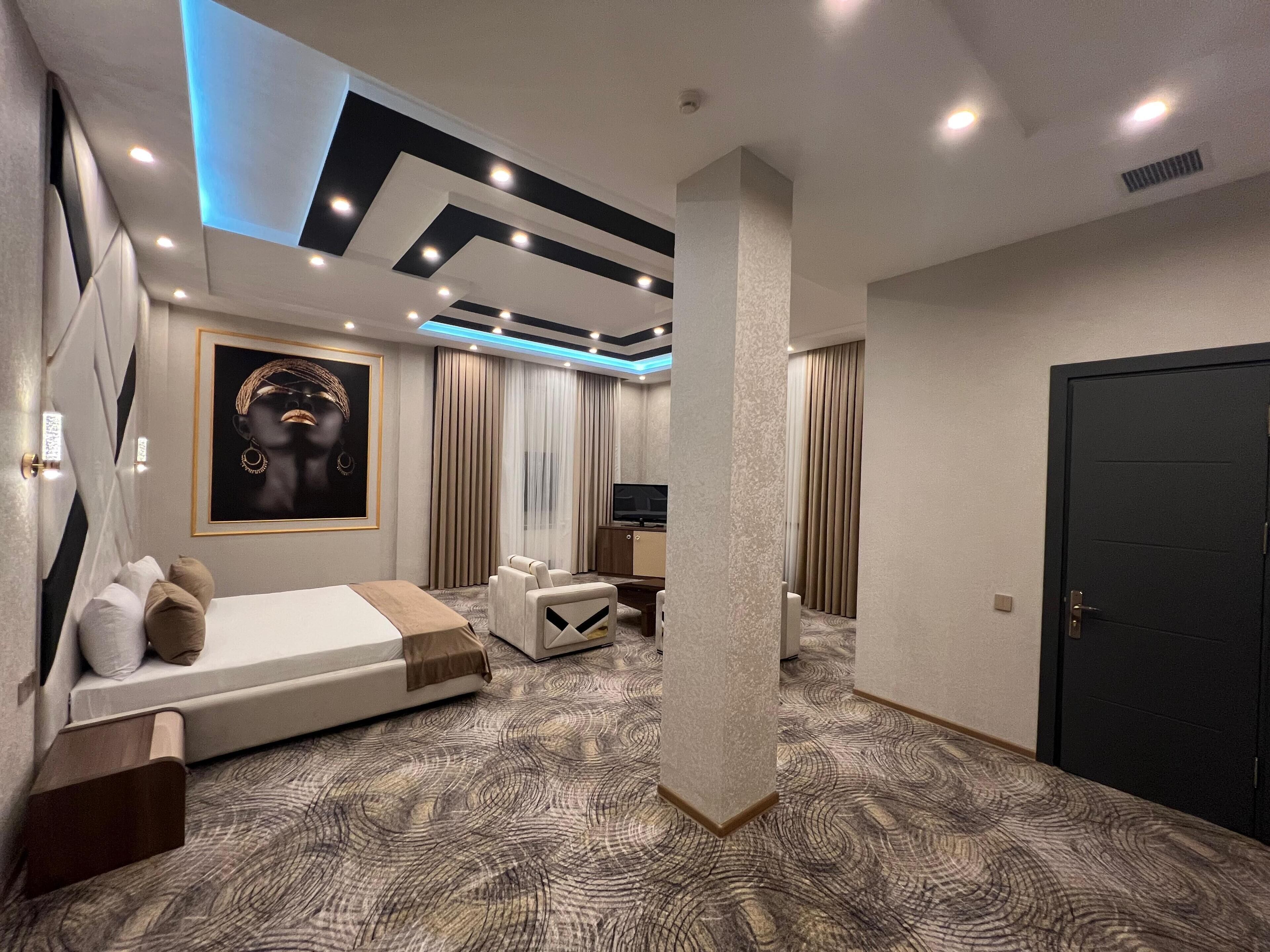 A modern hotel room with a bed, seating area, and a TV.