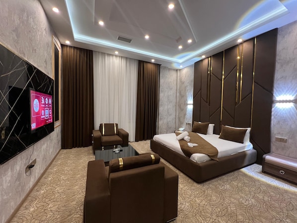 Una habitación de hotel moderna con una cama grande, un sofá, un televisor montado en la pared y un escritorio.