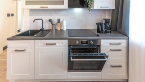 Una cocina moderna con horno empotrado, pileta y cafetera.