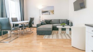Una sala de estar moderna con un sofá seccional gris, una mesita blanca y un comedor con sillas.