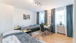A modern bedroom with a bed, desk, and chair, a radiator, and a window with curtains. - Hotel Essen (Essen)
