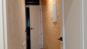 Ein enger Korridor mit Holzwänden und Holzboden, der zu einer Tür am Ende führt.