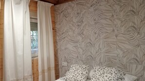 Ein Schlafzimmer mit Holzbalken, einem gemusterten Wandpapier und einem Bett mit gemusterten Kissen.