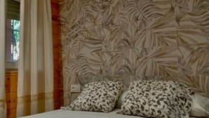 Ein Schlafzimmer mit einem Bett, Wandtapete mit Muster und einem Fenster mit Vorhängen.