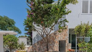 Una casa moderna con un muro de piedra y un árbol delante.