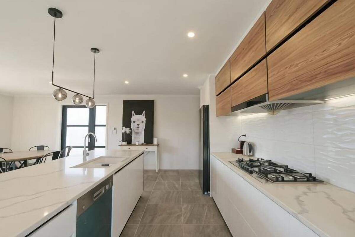 Eine moderne Küche mit einer großen Kochinsel, Holzschränken und einem weißen Kühlschrank.