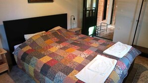 A bedroom with a large bed, a quilt, and two folded towels on the bed.