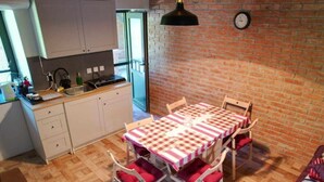 A cozy kitchen with white cabinets, a wooden countertop, and a red and white checkered tablecloth-covered dining table with four chairs.