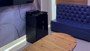 A modern living room with a flat-screen TV, a small black cabinet, a blue sofa, and a wooden coffee table.