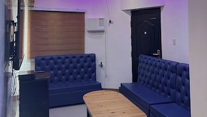 A modern living room with a blue sofa set, a wooden coffee table, and a ceiling with purple lighting.