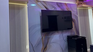 A modern interior with a mounted flat-screen TV, vertical blinds, and a decorative wall panel.