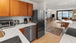 A modern kitchen with wooden cabinets, stainless steel appliances, and a view to the outside.