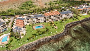 A resort with multiple buildings, a swimming pool, and a rocky shoreline.