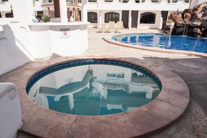 Relax by the pool with a hot tub and lounge chairs, surrounded by a decorative fountain and arched windows.