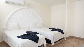Een kamer met twee bedden, elk met een wit hoofdeinde en een donge deken op één van de bedden.