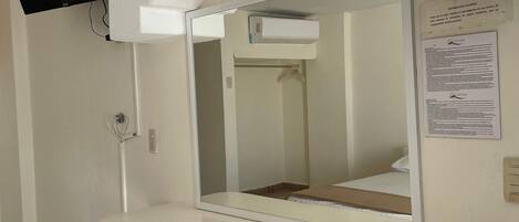 A room with a white counter, a mounted TV, and a wall-mounted air conditioner.
