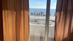 Een kamer met een bed, grote ramen en uitzicht op het strand en de oceaan.