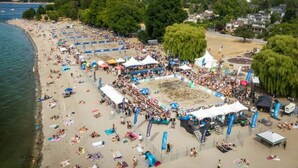 A beach with tents and people, a volleyball court, and a cityscape in the background. - Kitsilano Getaway - Near Beach - 10 min to Downtown (Vancouver)