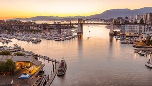 A marina with boats docked, a bridge, and buildings in the background. - Kitsilano Getaway - Near Beach - 10 min to Downtown (Vancouver)