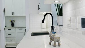 Una cocina moderna con armarios blancos, una isla grande, un grifo negro y una figurita decorativa de elefante.