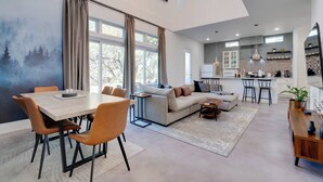 Un amplio salón con mesa de comedor, sofá y cocina al fondo.